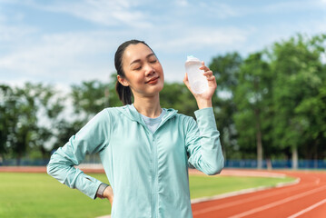 Beautiful asian woman holding drinking water bottle after running, She feeling fresh with sky...