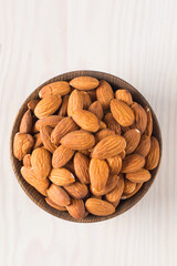 Raw peeled almonds in brown bowl