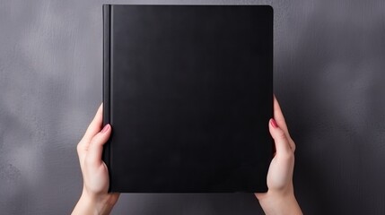 Vertical orientation captures female hands holding a large black book
