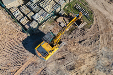 Aerial view of excavator working in quarry or construction site. Industrial top view background concept. A mining excavator is digging a pit. Rental of construction equipment. Contractor.