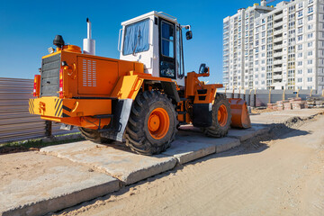 An orange and white construction vehicle is stationed on the side of a road, ready for work
