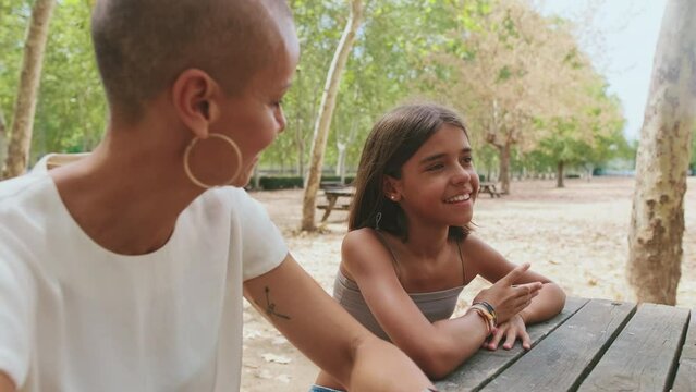 Close-up of happy mother and daughter sitting in the park and chatting