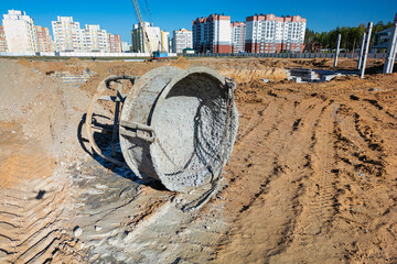 A large pipe is positioned in the center of a dirt field, showcasing construction work in progress