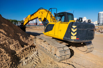 A yellow and black bulldozer actively digging into a pile of dirt at a construction site