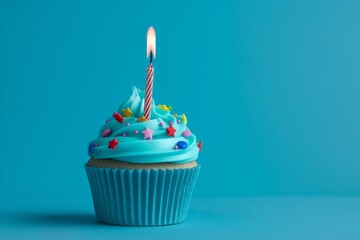 A single Birthday vibrant blue cupcake with candle and star shaped sprinkles on blue background