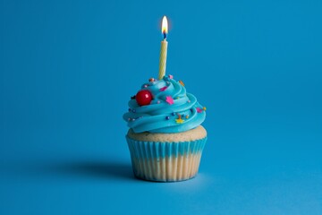 A single Birthday vibrant blue cupcake with candle and star shaped sprinkles on blue background