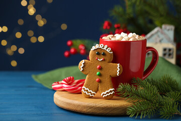 Tasty gingerbread man cookie and cocoa with marshmallows on blue wooden table. Space for text