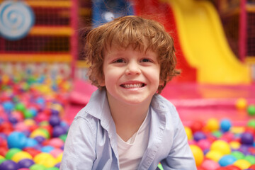 Happy little boy in ball pit. Kid's play room