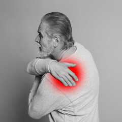 Senior man suffering from rheumatism on light background. Black and white effect with red accent in...