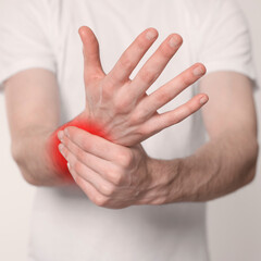Man suffering from rheumatism on light background, closeup