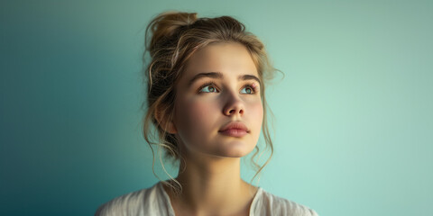 Young woman with a bun, looking up with hopeful eyes, light accentuating her delicate features