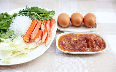 Sukiyaki food menu Marinated sliced ​​pork, eggs, vegetables, and compressed fish into bars. On the checkered table

