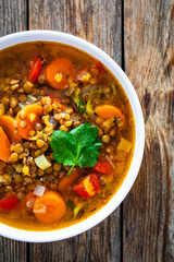 Fresh vegetable soup with lentil on wooden table
