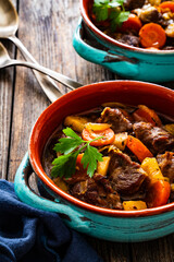Roast pork cheeks with carrots and celeriac in sauce on wooden table
