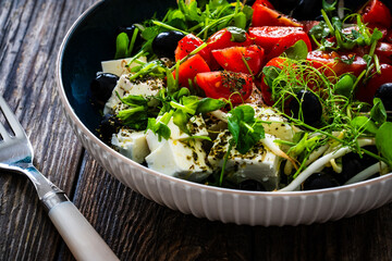 Greek style salad - fresh vegetables with feta cheese on wooden table

