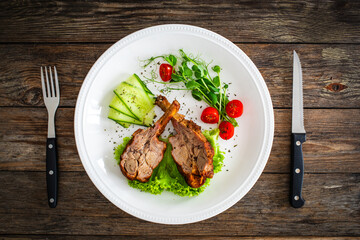 Lamb chops with bone and fresh vegetables on wooden table