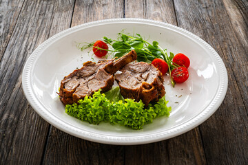 Lamb chops with bone and fresh vegetables on wooden table