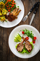 Lamb chops with bone and fresh vegetables on wooden table