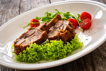 Lamb chops with bone and fresh vegetables on wooden table