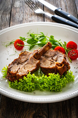 Lamb chops with bone and fresh vegetables on wooden table