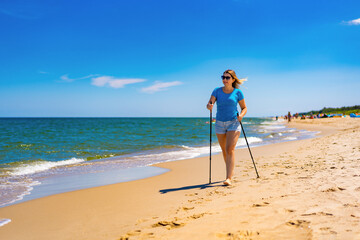 Nordic walking - beautiful woman exercising on beach 