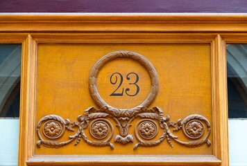 Une jolie façade en bois sculpté avec le nombre 23 au style ancien et poussiéreux