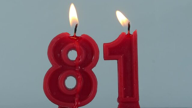close up on timelapse melting a red number eighty one birthday candle on a white background.

