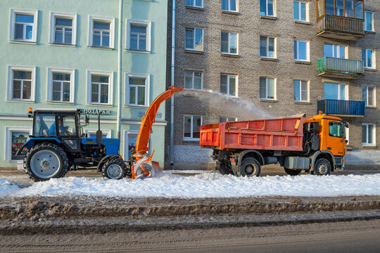 KRONSTADT, RUSSIA - JANUARY 18, 2022:  Tractor MTZ-82.1 tractor with a mounted snow blower clears snow from the sidewalk of a city street