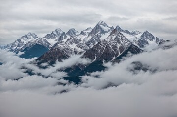 Majestic mountains capped with snow rise above swirling clouds in serene atmosphere 