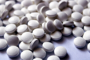 A lot of white pills are scattered on a white background.