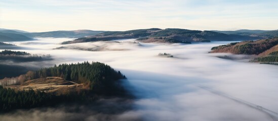 Fototapeta premium Aerial view of mountain peak with green trees in fog