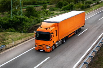 Fototapeta na wymiar Large orange Transportation Truck on a highway road through the countryside