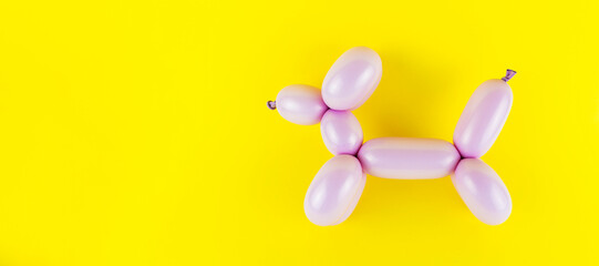 Pink craft balloon dog isolated on the yellow background