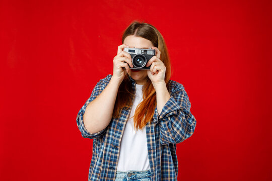 Young 30s photographer is taking a photo isolated over red background. Home hobby, lifestyle, travel, people concept