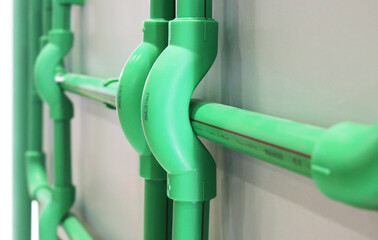 Green polypropylene sanitary pipeline installed on building wall.