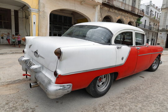 Oldtimer red-white almendron car -yank tank, Oldsmobile classic- from 1954 stops on the Plaza del Cristo Square. Old Havana-Cuba-041