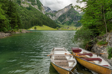 Beautiful summer view on lake Seealpsee in the Swiss alps, 2 rowing boats are lying in the water in...