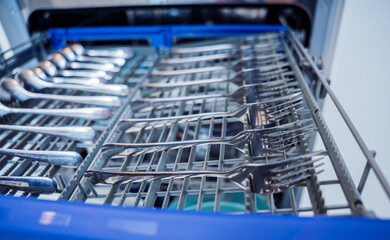 The white kitchen and opened dishwasher with clean dishes