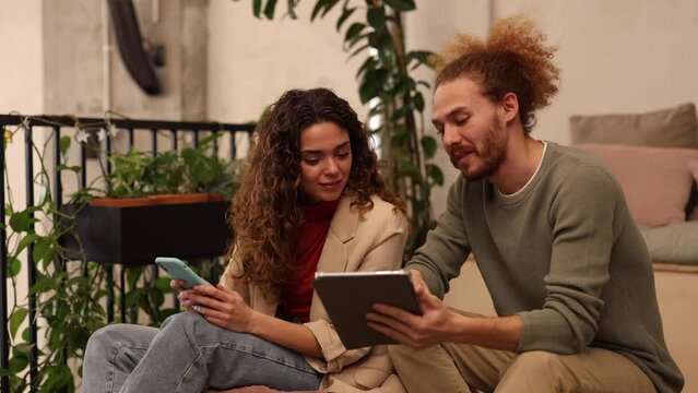 Young coworking coworkers meeting using digital tablet, young caucasian woman with curly hair with redhead man.