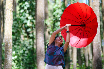 Woman's red umbrella blown away by the wind while walking alone in the park