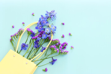 Top view image of violet delphinium flowers composition over blue background