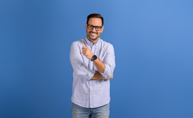 Portrait of successful male manager in eyeglasses smiling at camera on isolated blue background
