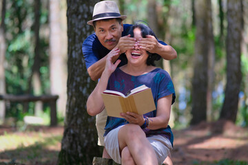 Man covering a woman's eyes with both hands from the back, while she was reading a book