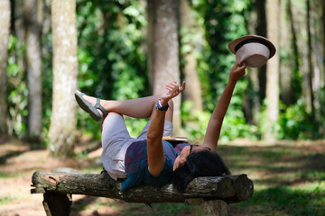 Woman lying on a log bench in the park, stretching after taking a long nap