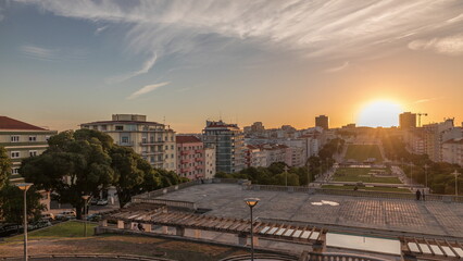 Naklejka na ściany i meble Panorama showing sunset over lawn at Alameda Dom Afonso Henriques and the Luminous Fountain aerial timelapse in Lisbon.