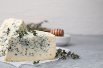 Tasty blue cheese with thyme on grey table, closeup. Space for text