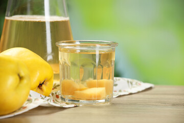 Delicious quince drink and fresh fruits on wooden table against blurred background, closeup