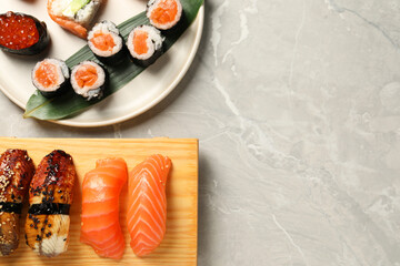 Delicious sushi rolls on light grey marble table, flat lay. Space for text