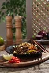 Stir-fry. Tasty noodles with meat and vegetables served on wooden table