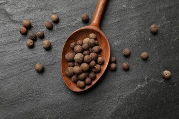 Dry allspice berries (Jamaica pepper) on black table, top view - obrazy, fototapety, plakaty